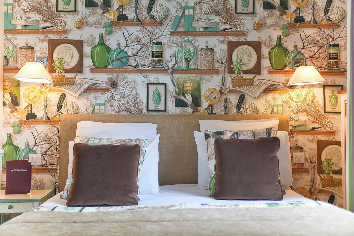 Una habitación de hotel con una cama, dos lámparas y una pared decorada con diversos objetos.