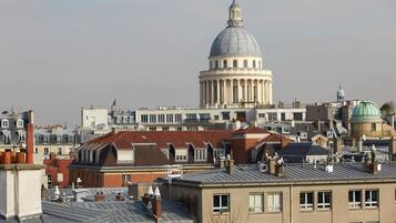 Un paisaje urbano con un edificio de cúpula destacado en el centro, rodeado de edificios residenciales con diferentes tejados y estilos arquitectónicos.