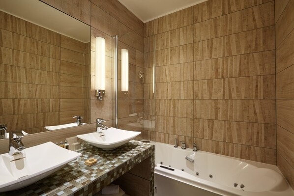 Un bagno moderno con due lavabi, uno specchio grande e una vasca da bagno.