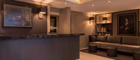 A modern lobby with a marble reception desk, a sofa set, and framed artwork on the walls.