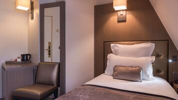 Una habitación de hotel moderna con una cama, un escritorio y una silla. Hay luces empotradas sobre la cama y un espejo en la pared.
