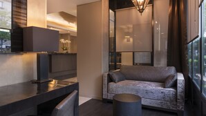 Un espacio de sala moderno con un escritorio de madera oscura, un sofá gris y una mesa redonda.
