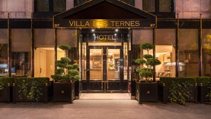 La entrada del Hotel Villa de Ternes, con una fachada clásica, amplias ventanas arqueadas y una entrada acogedora.