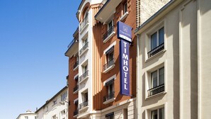 En hotellbyggnad med flera våningar, med en tydlig skylt som visar texten ”TimHotel Paris”.