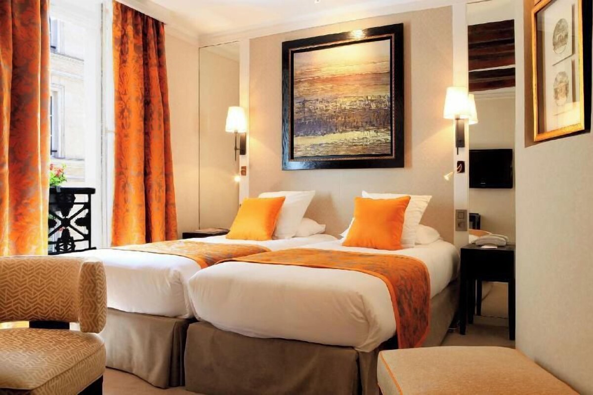A hotel room with two beds, a sofa, a desk, and a painting on the wall.