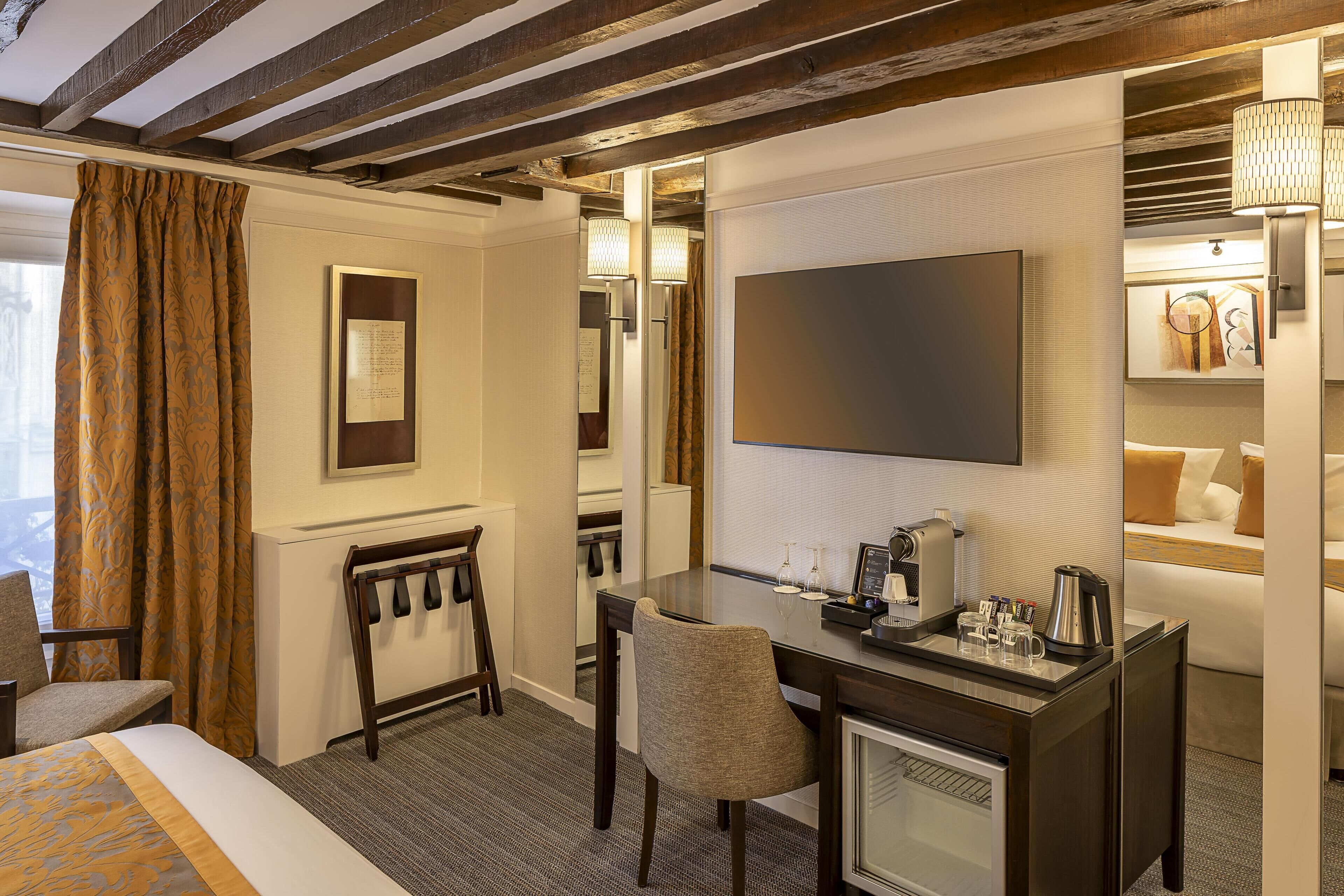 Una habitación de hotel con cama, escritorio, cafetera, televisor y silla.