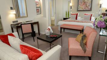 Une chambre d’hôtel équipée d’un canapé, d’un fauteuil, d’un lit, d’une table de chevet et d’un petit bureau avec une chaise.
