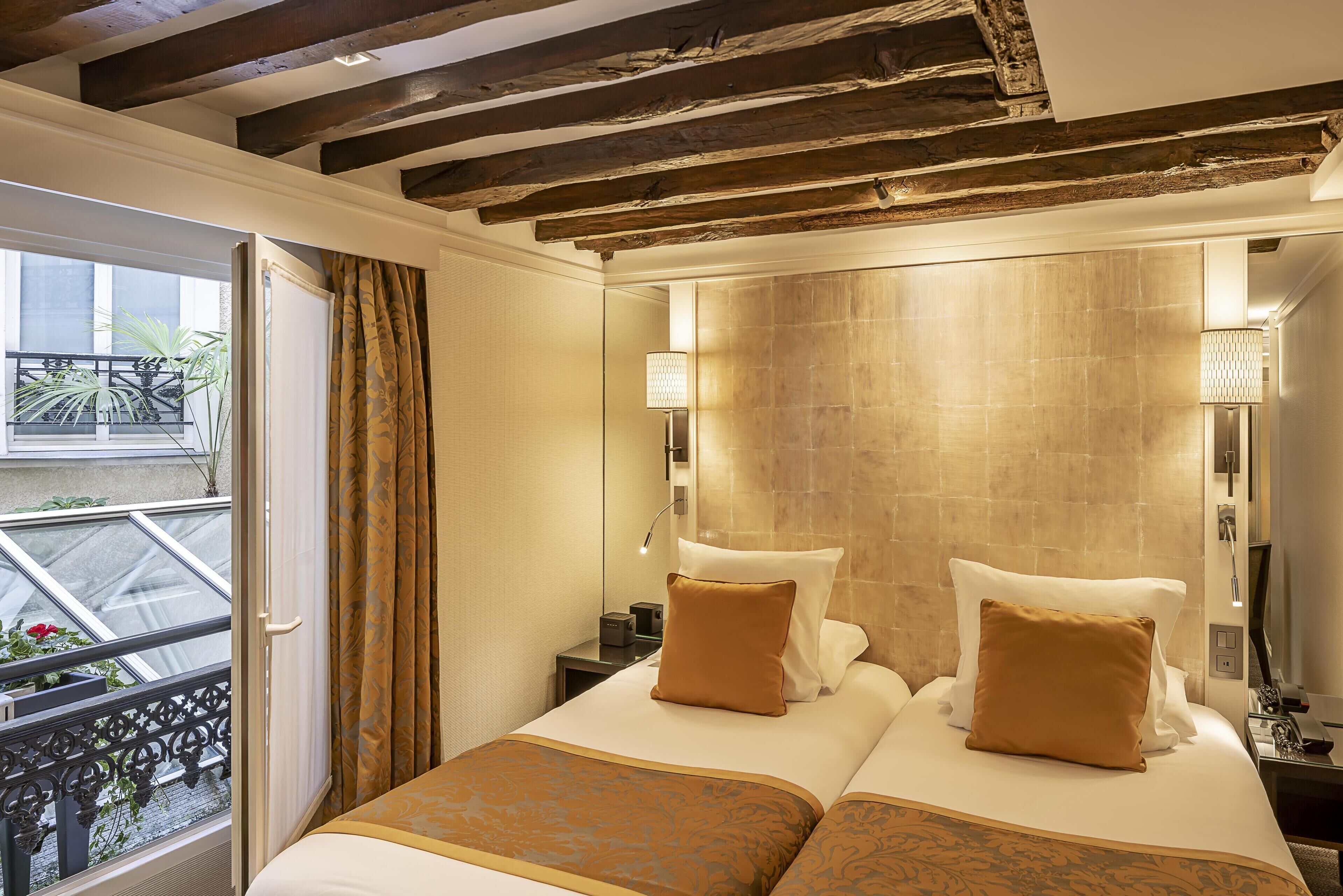 Habitación de hotel con una cama grande, un balcón con vistas y un baño moderno con un espejo amplio y toallero.