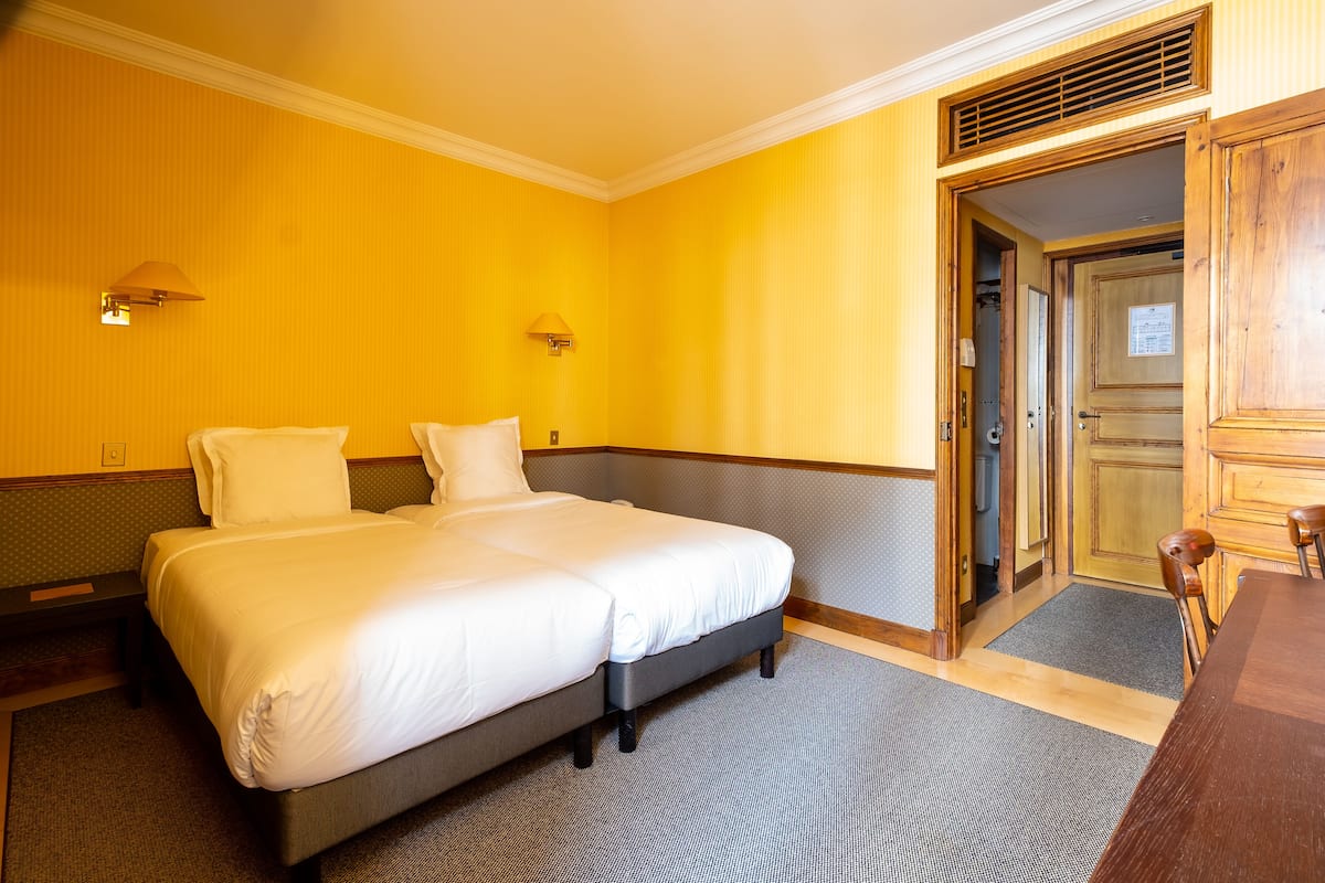 Une chambre d’hôtel avec un lit double, deux lampes de chevet, une porte en bois et une petite table.