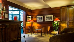 A bar area with wooden paneling, a bar counter, and a seating arrangement with chairs and a table. - Le Relais Monceau (Paris)