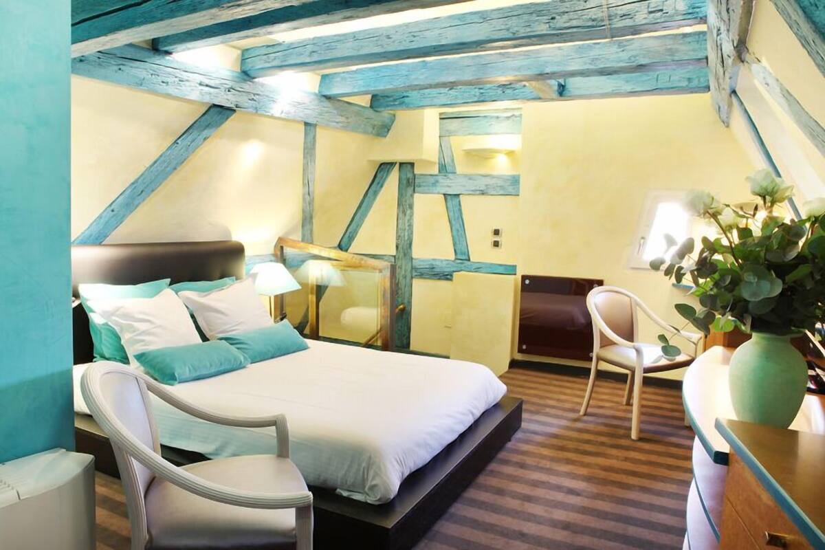 A bedroom with a bed, bedside tables, a chair, and a potted plant.