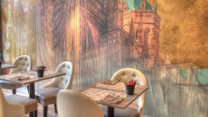 L’intérieur d’un restaurant, avec une fresque représentant un bâtiment historique, des tables dressées et des chaises rembourrées.