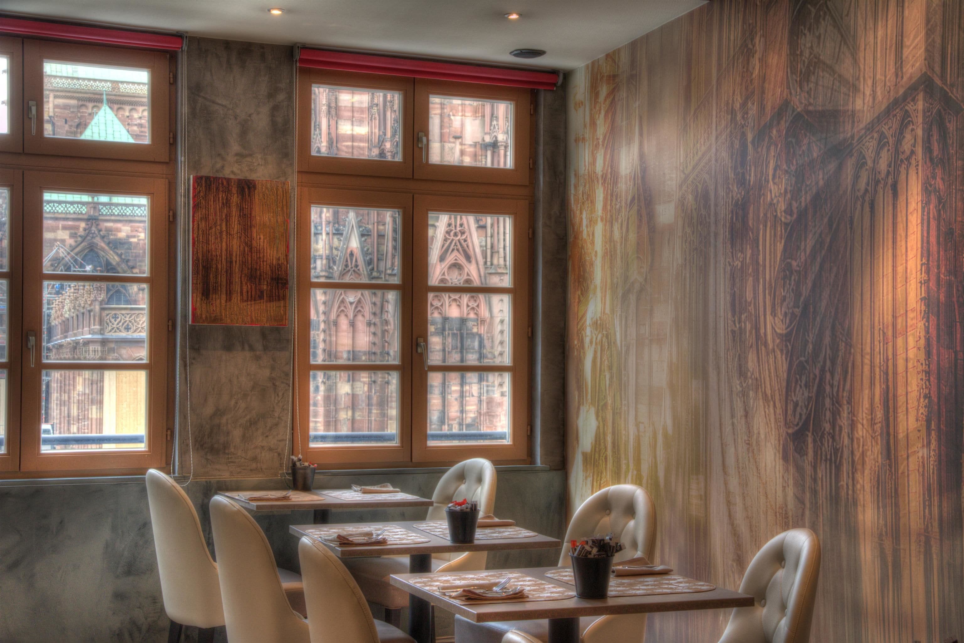 Ein Restaurant mit großen Fenstern, Holztischen und -stühlen.