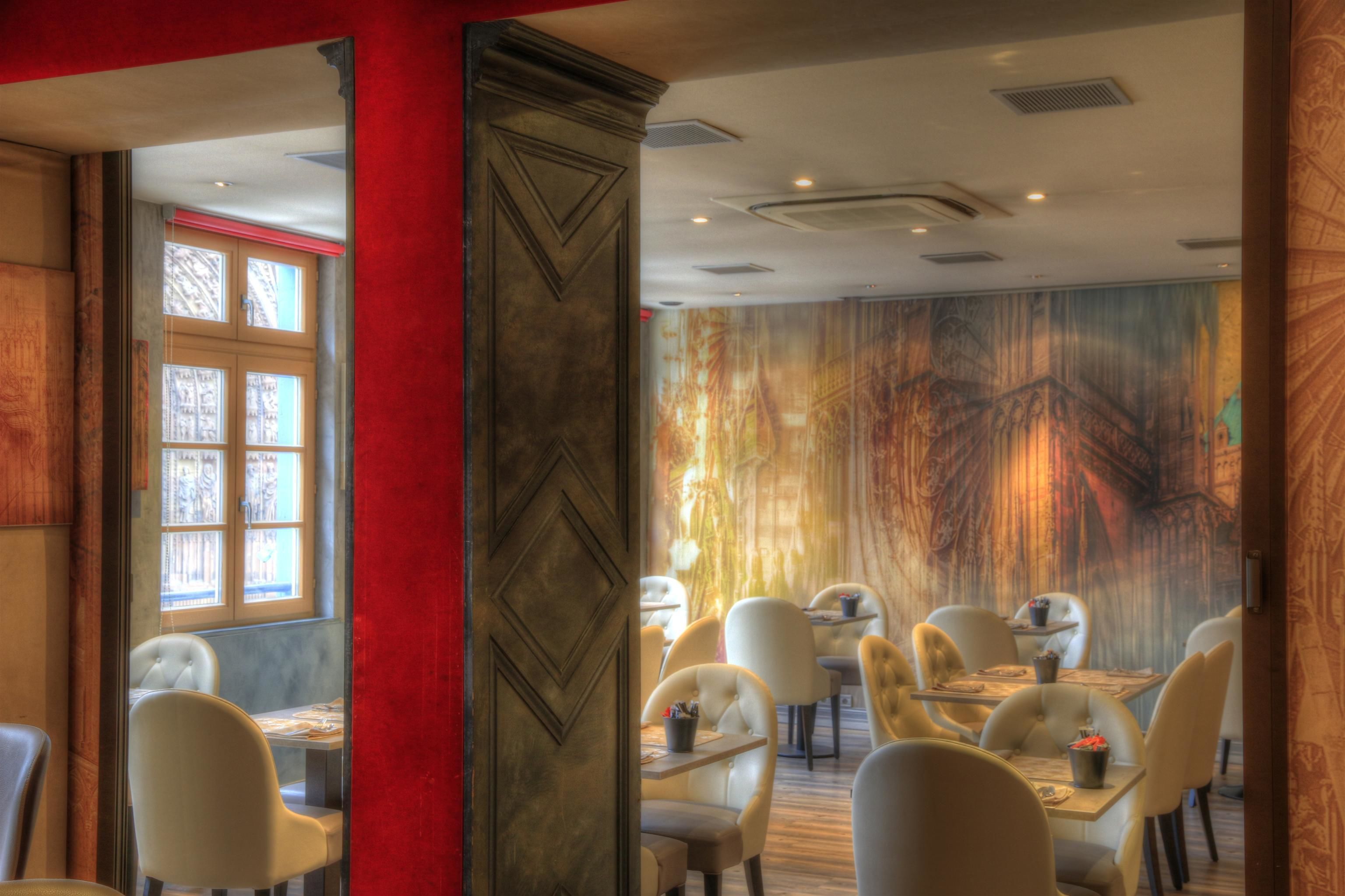 Un restaurant au décor moderne, avec un mélange de meubles en bois et de meubles rembourrés, et une grande fresque murale sur le mur du fond.
