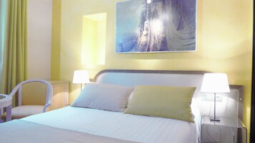Una habitación de hotel con una cama, dos lámparas de noche, una silla y un cuadro en la pared.