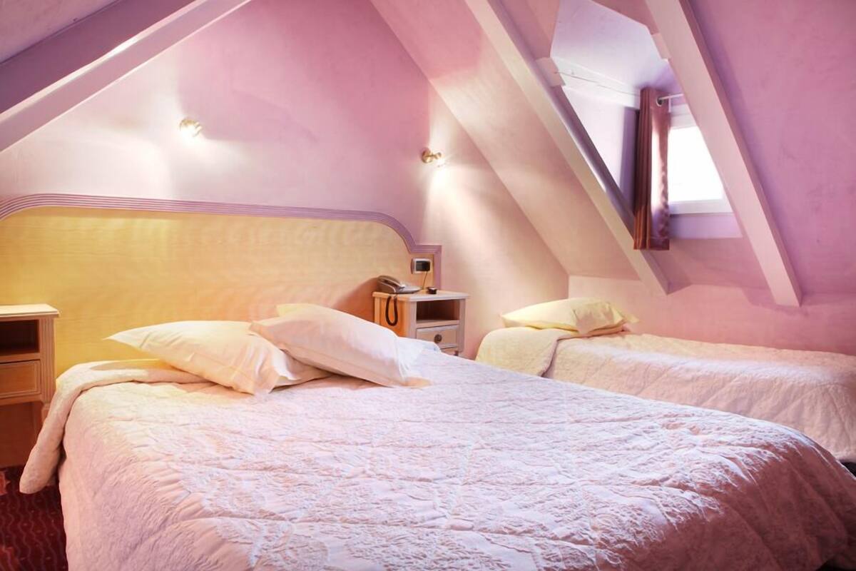 A bedroom with two beds, a nightstand, and a small table with a lamp.