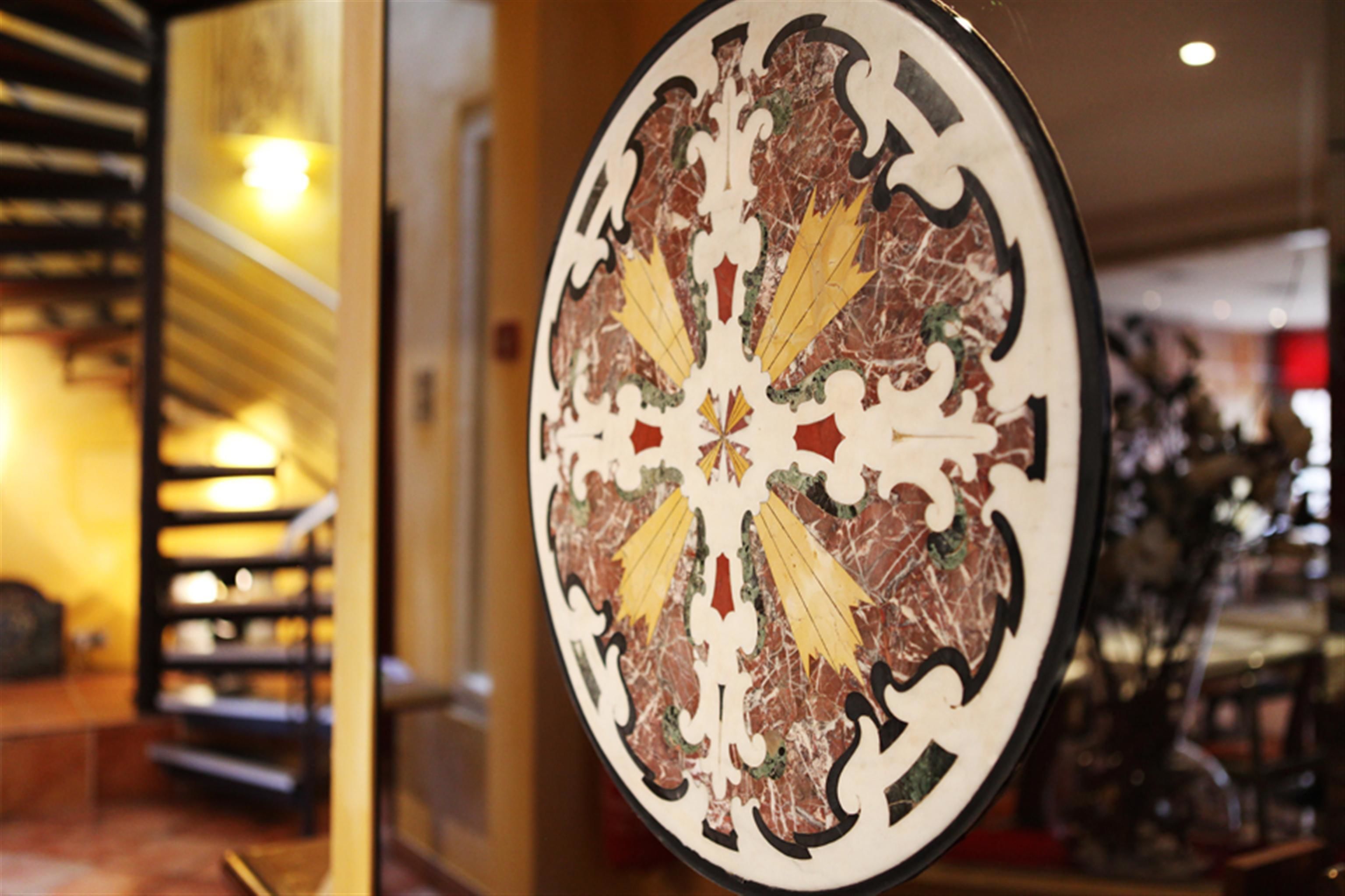 A circular decorative piece with a central floral motif, surrounded by a black border.