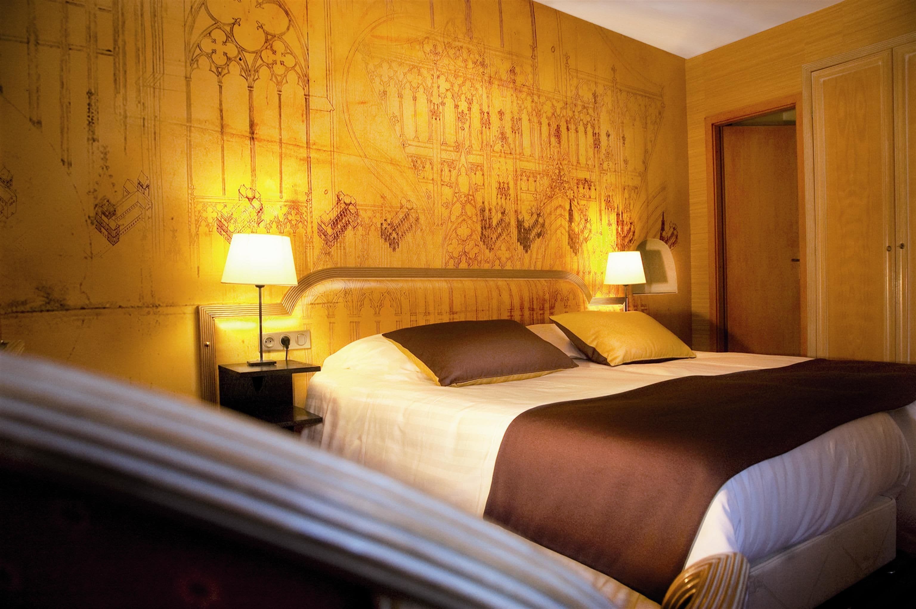Une chambre d’hôtel avec un grand lit, deux lampes de chevet et une fresque décorative sur le mur.