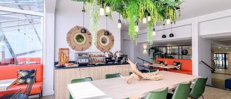Una cocina moderna con una mesa de madera, sillas verdes y plantas colgantes.