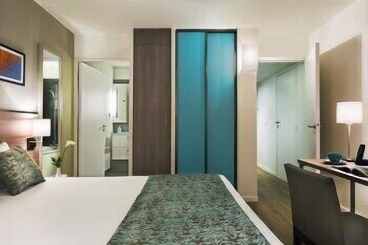 A hotel room with a bed, a desk, a chair, a wardrobe, and a bathroom.