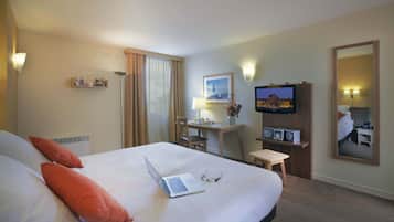 Een hotelkamer met een bed, een bureau met een laptop, een televisie en een klein tafeltje met een vaas.