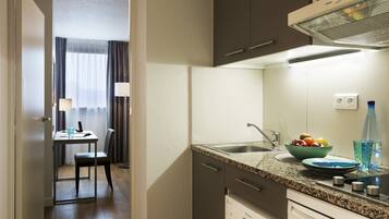 A modern kitchen with a granite countertop, stainless steel sink, and a Siemens dishwasher.