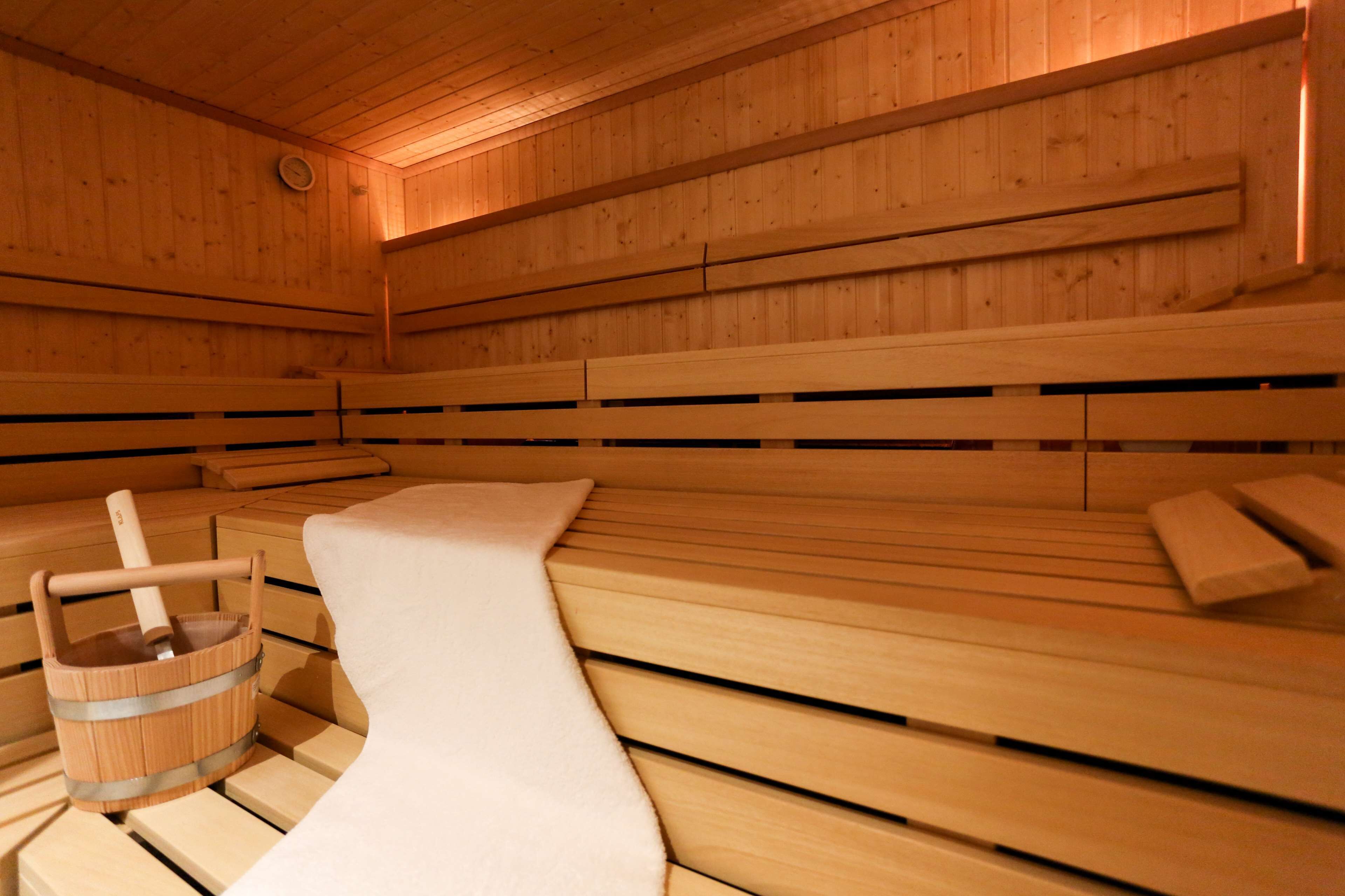 A sauna with wooden benches and a wooden bucket.
