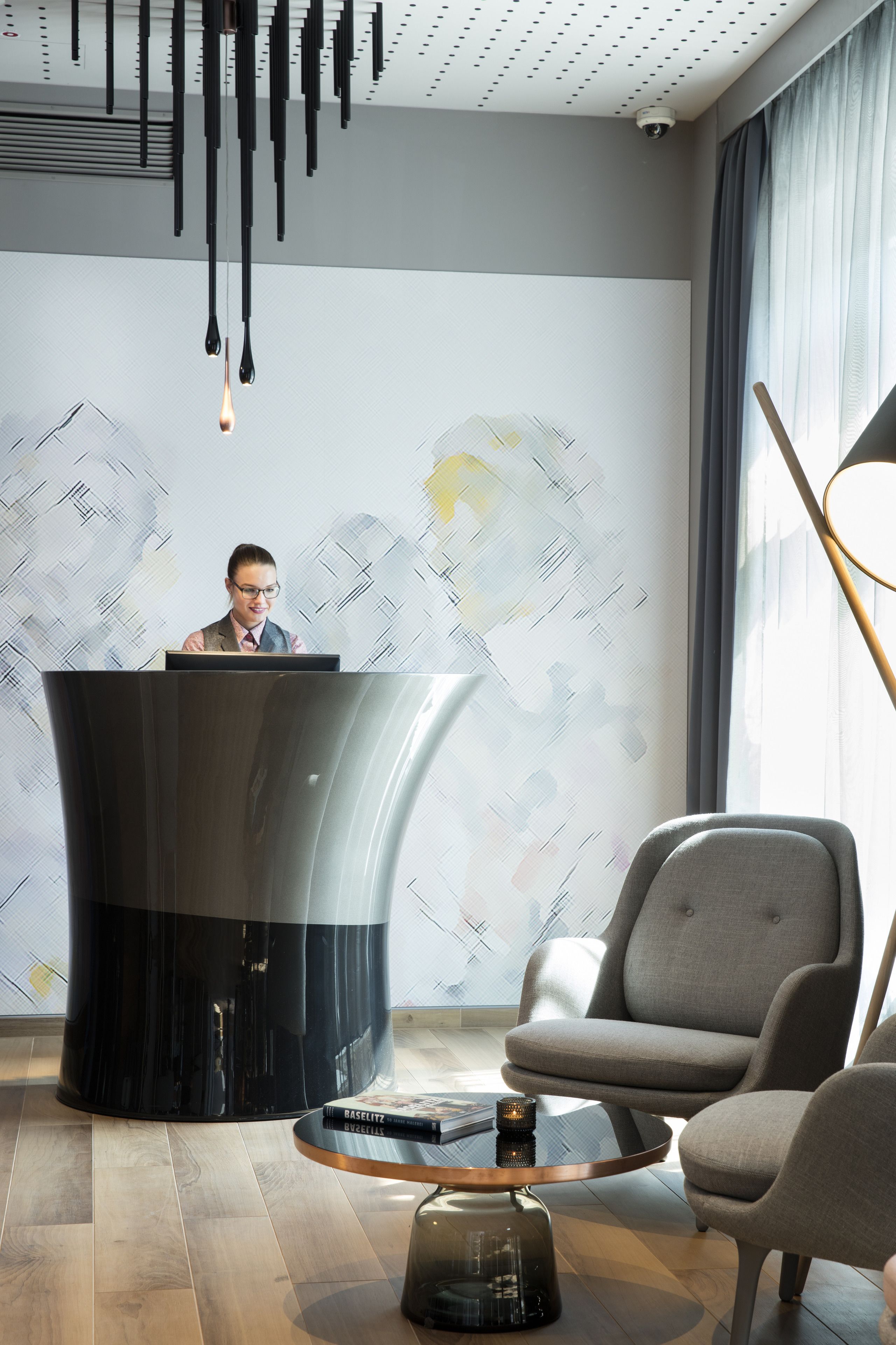 A modern office with a curved black desk, a person at the desk, and a patterned wall.