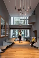 Un'ampia hall con sedute moderne, soffitto alto e grandi finestre che lasciano entrare la luce naturale.