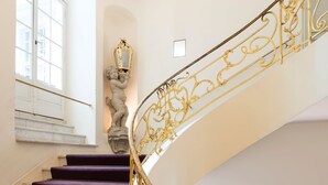 A curved staircase with purple carpeted steps and ornate golden railings. - art'otel Berlin Mitte (Berlin)