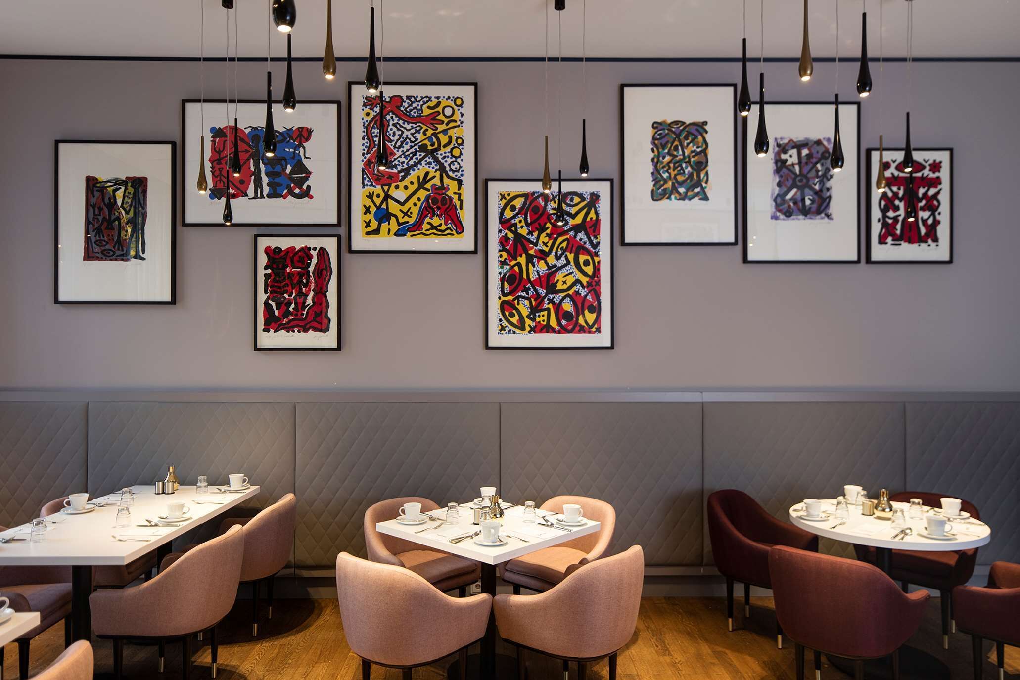A modern dining area with tables set for service, framed abstract art on the walls, and a clean, contemporary design.