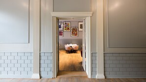 A hallway with a dining area, featuring a brick wall, white columns, and a wooden floor. - art'otel Berlin Mitte (Berlin)