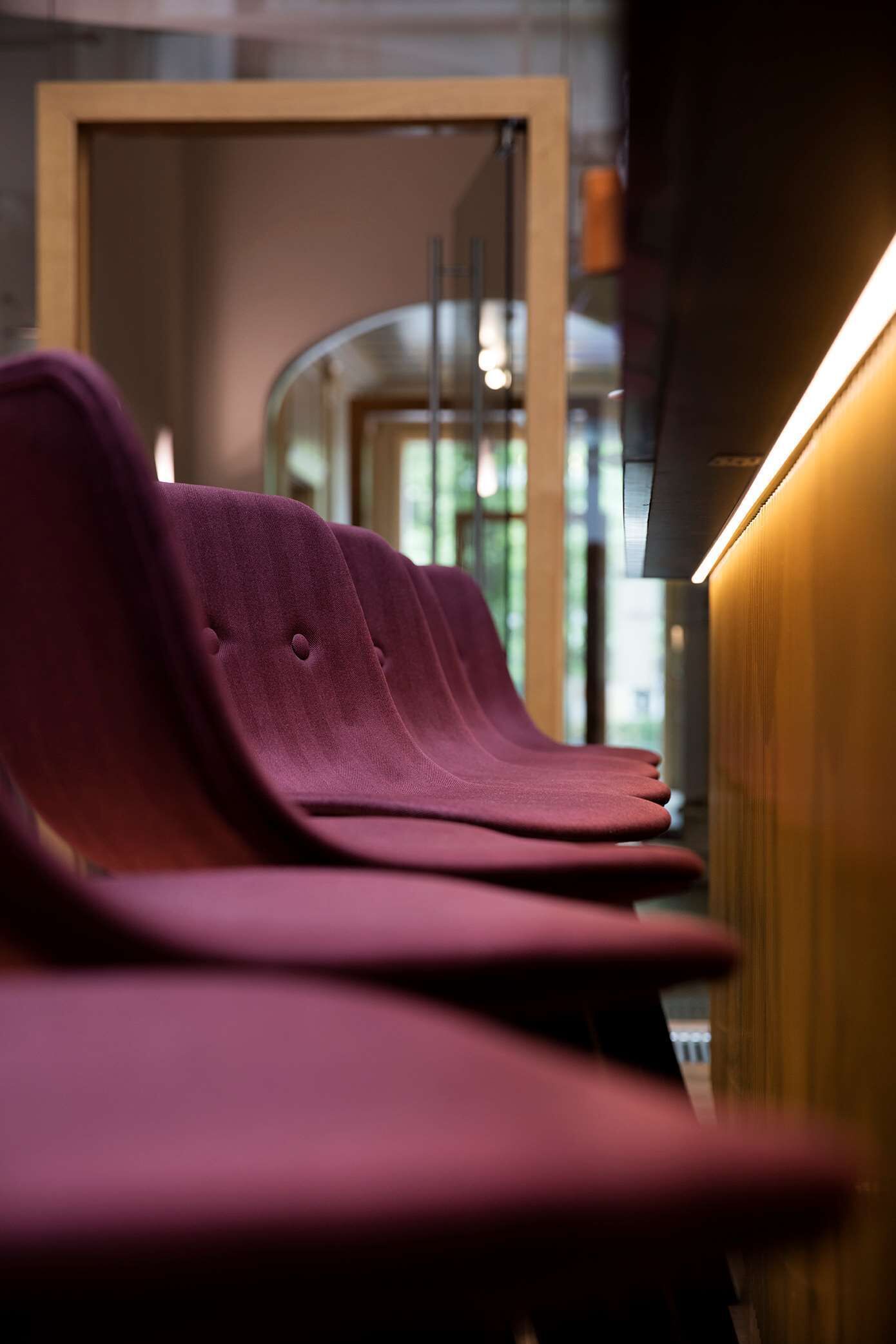 A row of purple chairs with a wooden frame and a glass partition in the background.