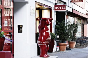 Ingresso di un hotel con una statua rossa di un orso e un cartello che indica la disponibilità di autentica cucina thailandese.