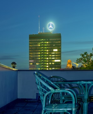 Un edificio moderno con un logo ben visibile in alto, una gru edile nelle vicinanze e una sedia in metallo in primo piano.
