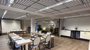 Uma sala de conferência moderna com uma mesa comprida, cadeiras e uma tela de projetor.