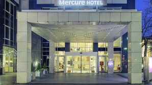 The exterior of the Mercure Hotel with a modern facade, large glass entrance, and a sign above the doors.