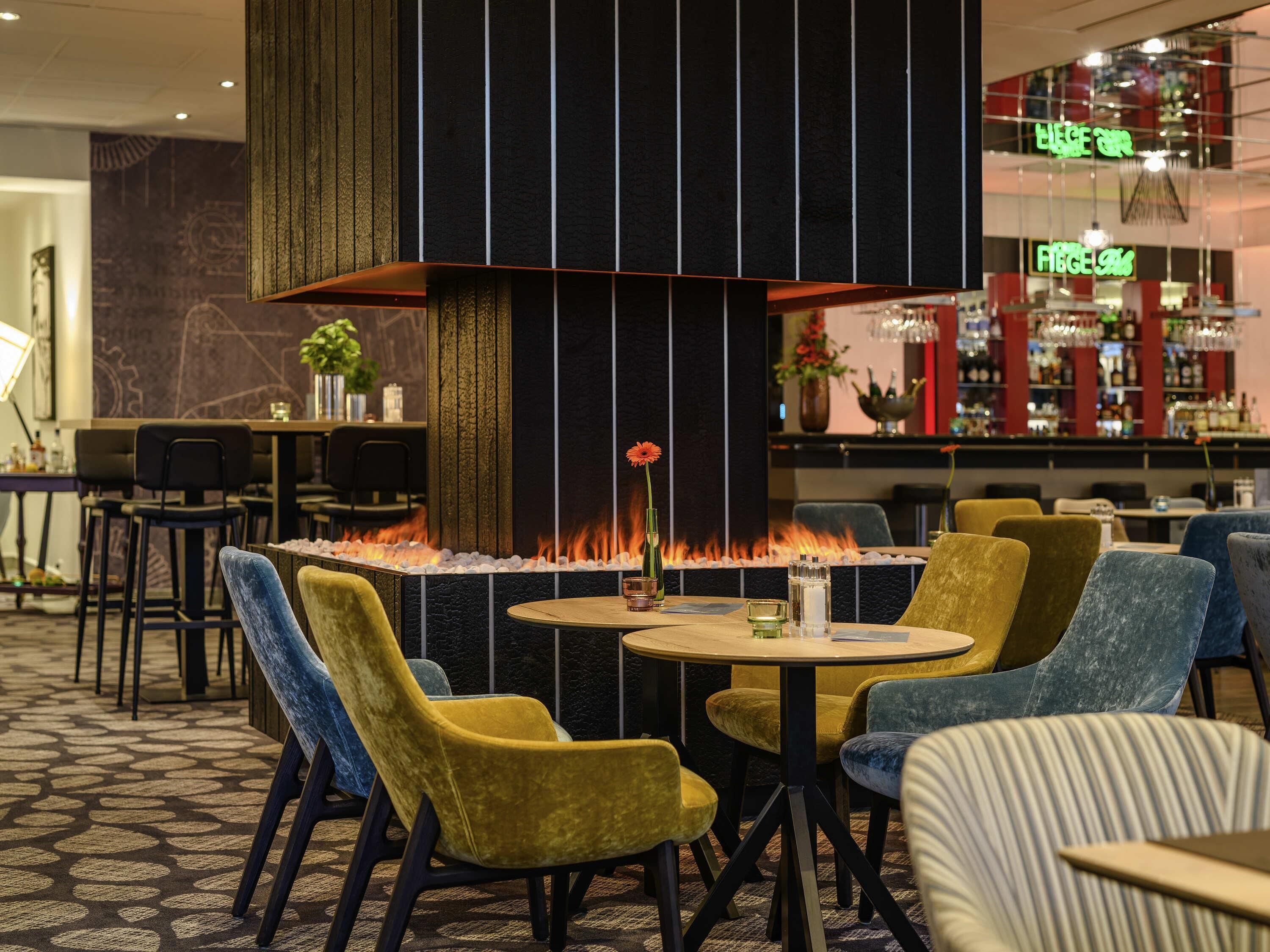 A modern bar area with a fire feature, seating, and a bar stocked with bottles.