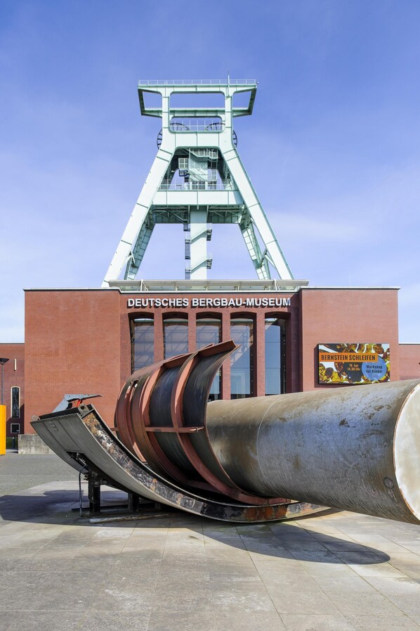 A large industrial structure with a sign reading "DEUTSCHES BERGBAU-MUSEUM" and a large cylindrical object in front.