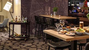 Ein Essbereich mit Tisch für zwei Personen, eine Bar und eine Wand mit technischen Zeichnungen.