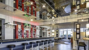 A modern bar area with multiple stools, a bar counter, and a variety of bottles and glasses.