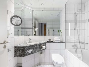 A modern bathroom with a granite countertop, a toilet, a shower, and a large mirror. - Mercure Hotel Bochum City (Bochum)