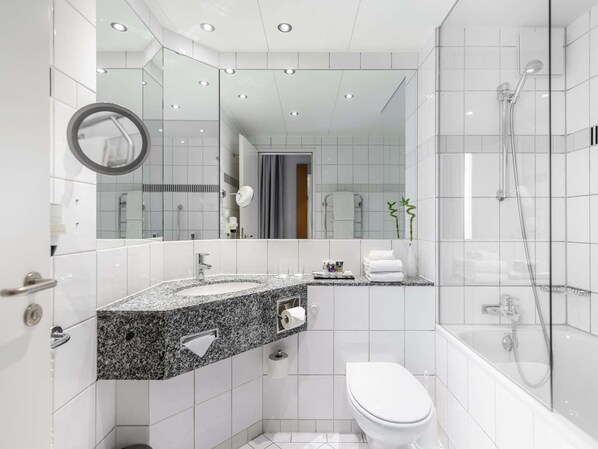 Une salle de bain moderne avec un comptoir en granit, des toilettes, une douche et un grand miroir.
