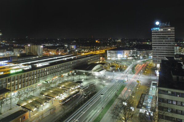 Una estación de tren moderna con varias vías y un edificio grande con un cartel llamativo.