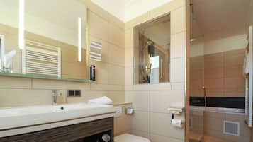 A modern bathroom with a large mirror, a sink, a toilet, and a shower area.