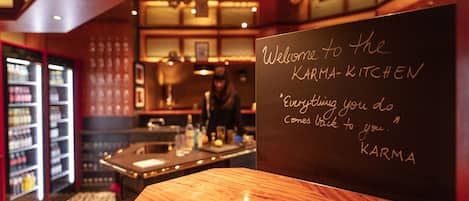 Een schoolbordbord in een restaurant met de tekst 'Welkom bij KARMA-KITCHEN 'Wat je zaait, zul je oogsten.' KARMA'.