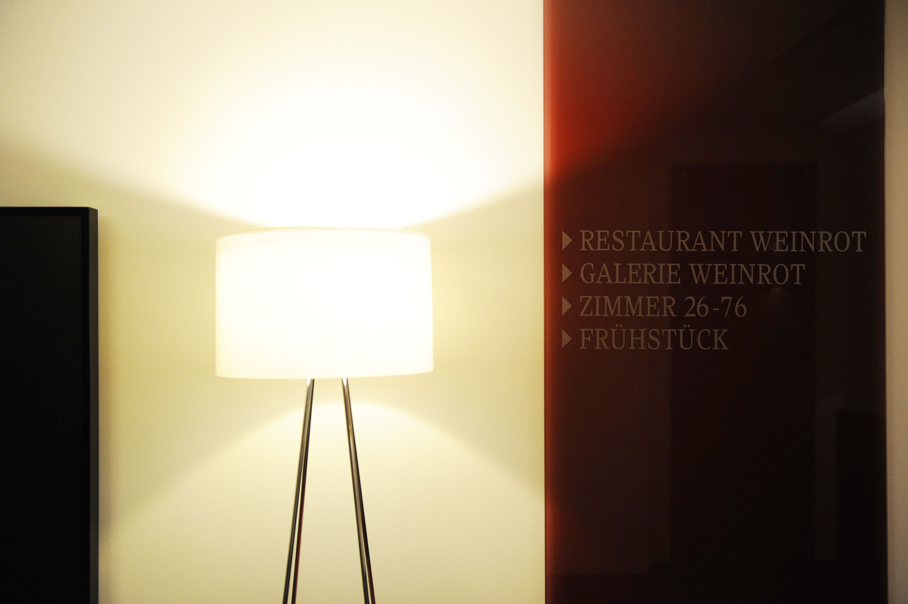 Un mur orné d’une lampe et d’un texte indiquant les détails concernant le restaurant, la galerie et les chambres.