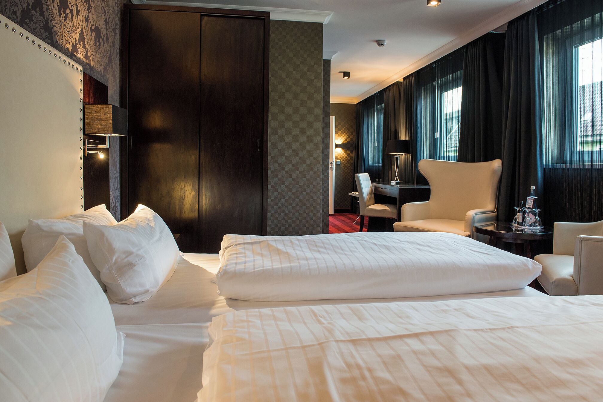 Una habitación de hotel con una cama grande, un escritorio, una silla y un armario.