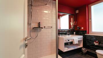 A modern bathroom with a glass-enclosed shower, a white sink, and a black tiled floor.