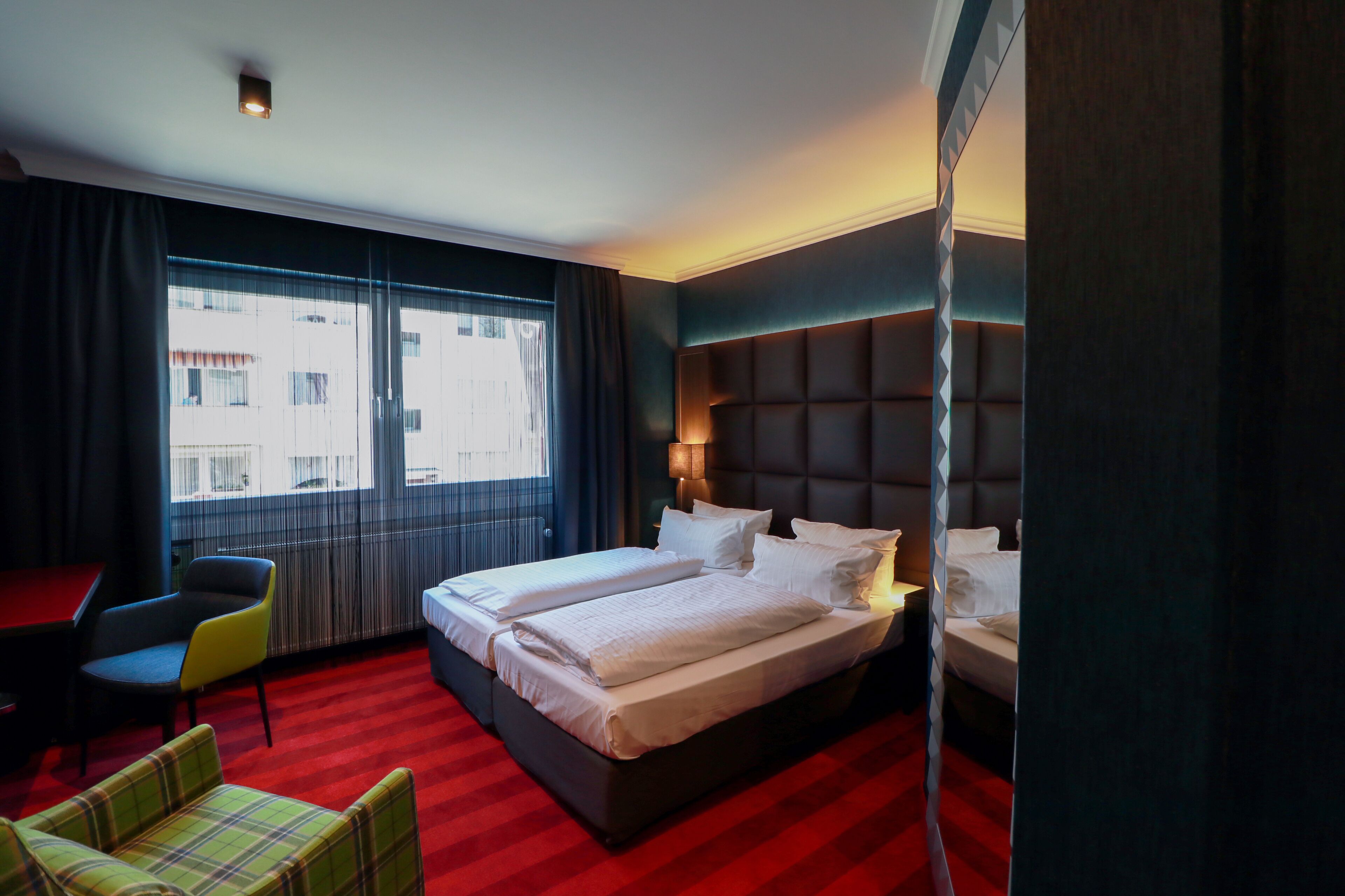 A hotel room with a large bed, a desk, and a chair.